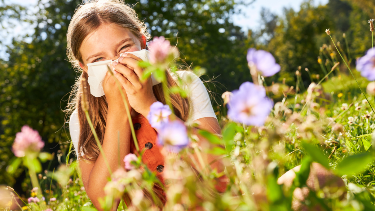 Girl in field of flowers blowing her nose in a tissue