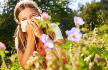 Girl in field of flowers blowing her nose in a tissue